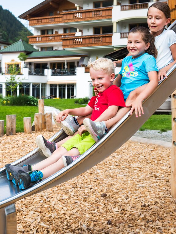 Drei Kinder rutschen auf einer Rutsche im Freien