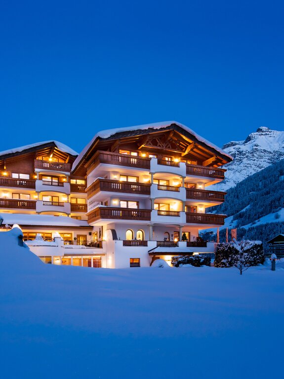 Stubaierhof im Schnee bei Nacht mit beleuchteten Fenstern und Bergen im Hintergrund