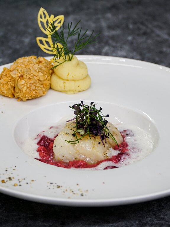 Feines Gericht auf weißem Teller: Fisch, Kartoffelpüree, Kruste, Dekoration