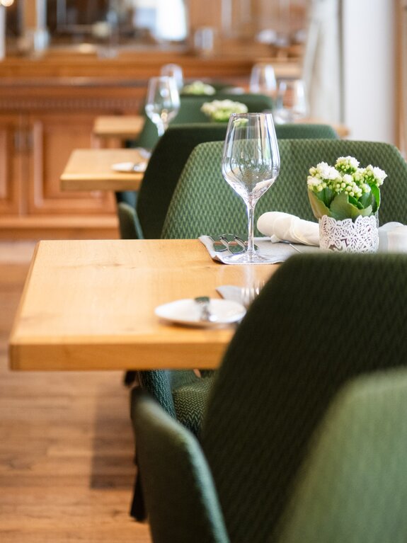 Gedeckte Tische in einem Restaurant mit grünen Stühlen und Holzboden