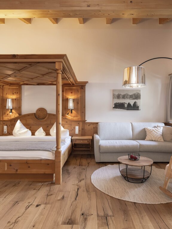 Helles Schlafzimmer mit Holzbett, Sofa, Lampe und Holzboden