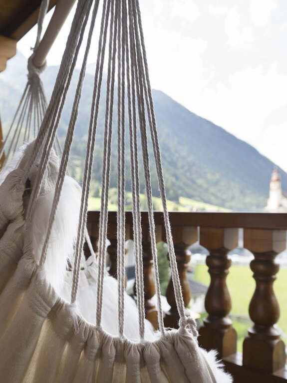 Hängesessel auf Balkon mit Blick auf grüne Landschaft und Berge