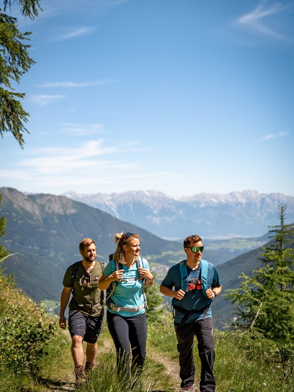 Die Gastgeber Martina, Andreas und Daniel wandern  in Berglandschaft mit Blick über das Stubaital
